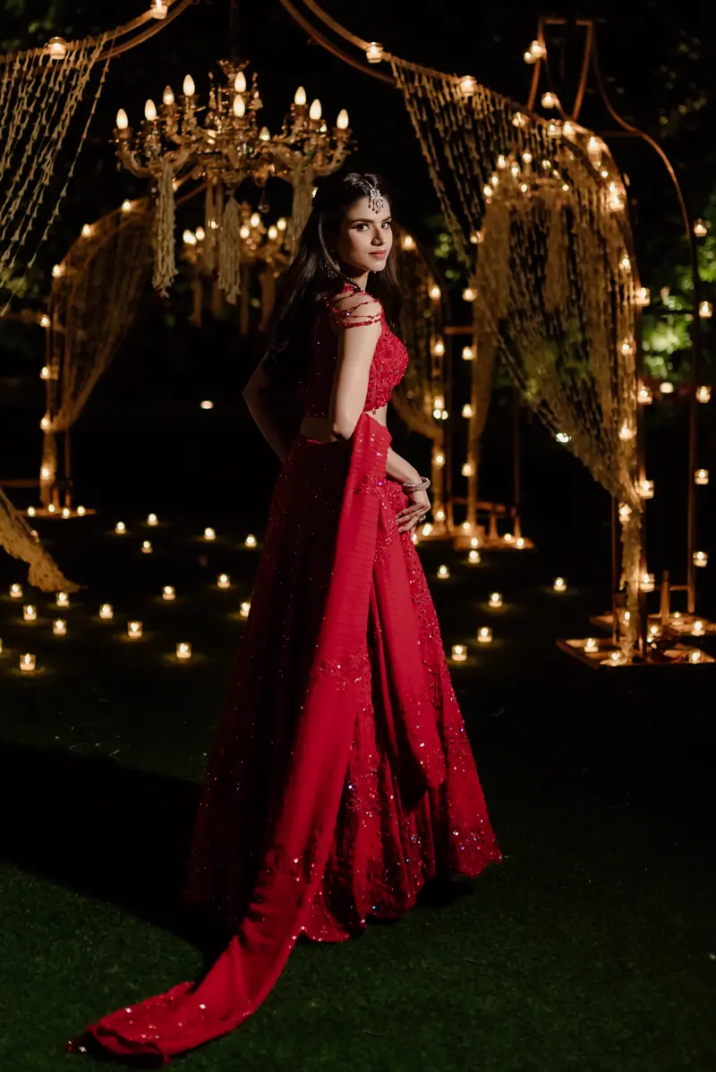 A guest in red under strings of light at a sufi night