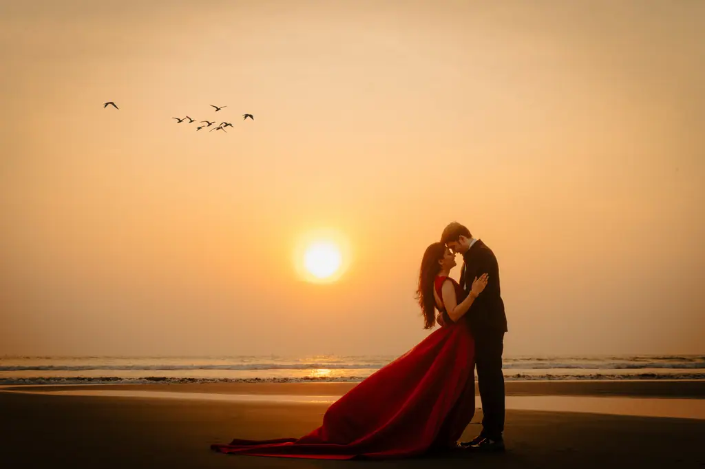A couple silhouetted against a sunset on an empty beach